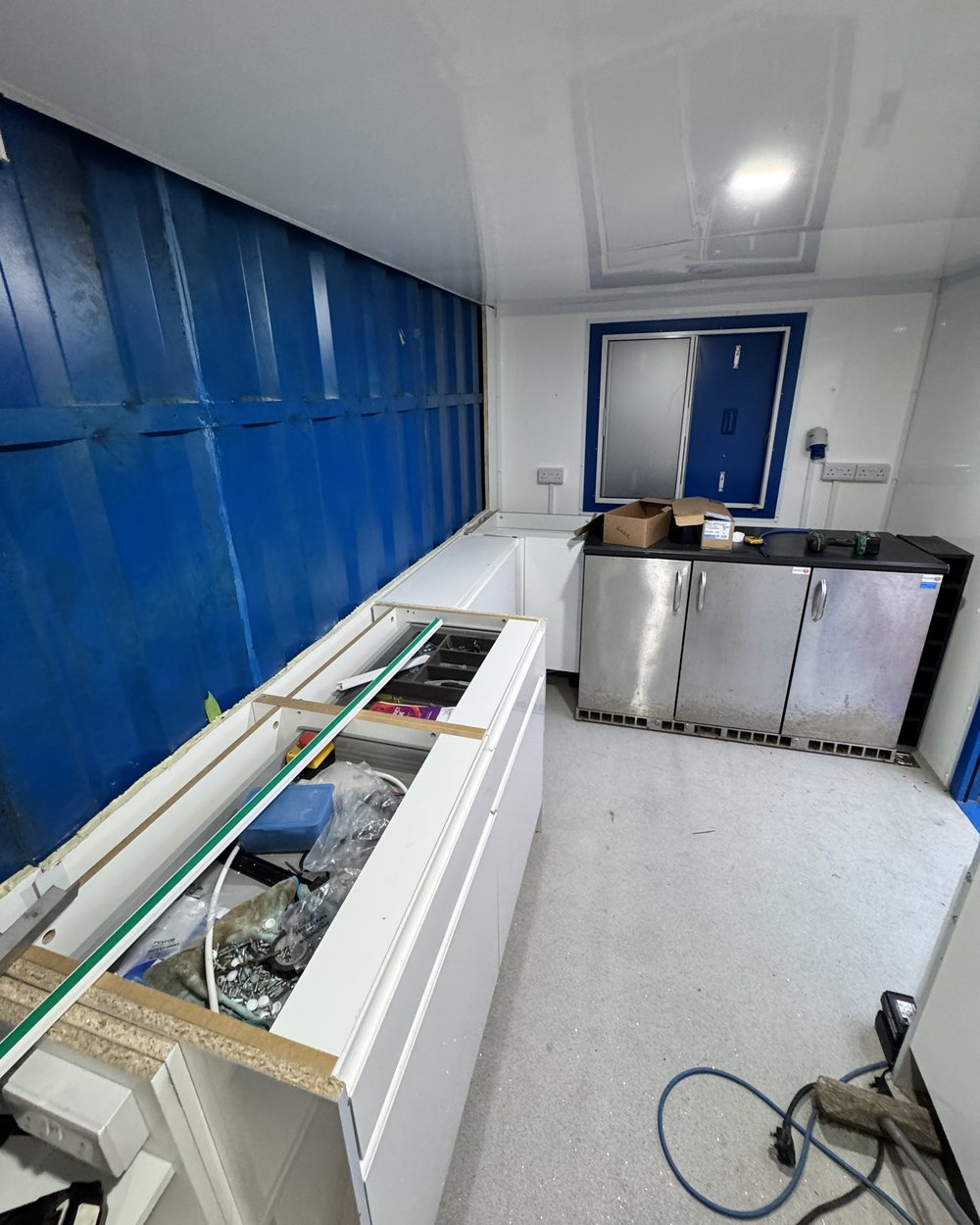 Inside a unit during the build: white cabinets and under-counter fridges set out