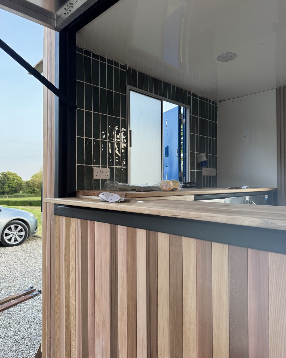 A finished unit: vertical timber cladding, solid timber counter and green tiled interior