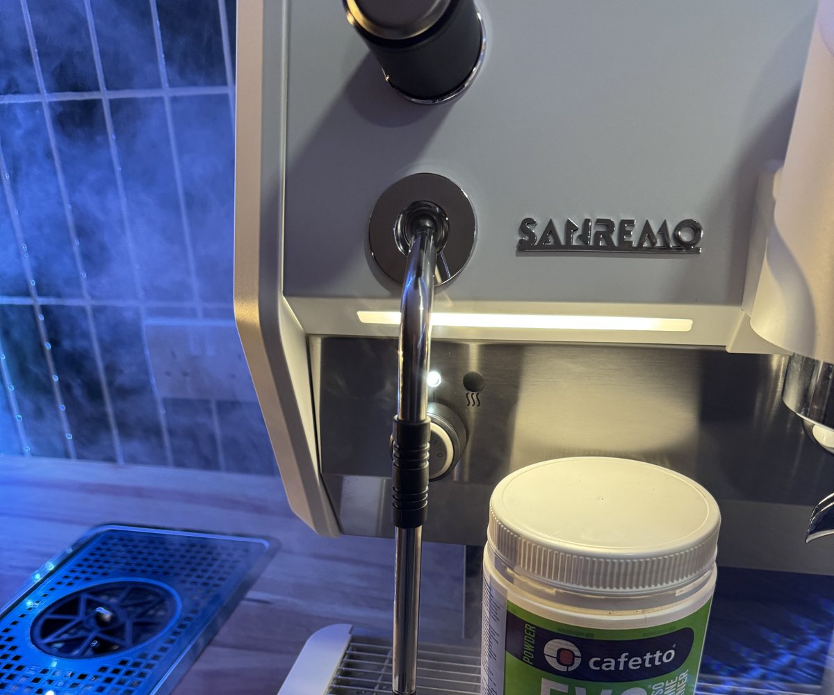 Close-up of a commercial espresso machine steam wand and drip tray