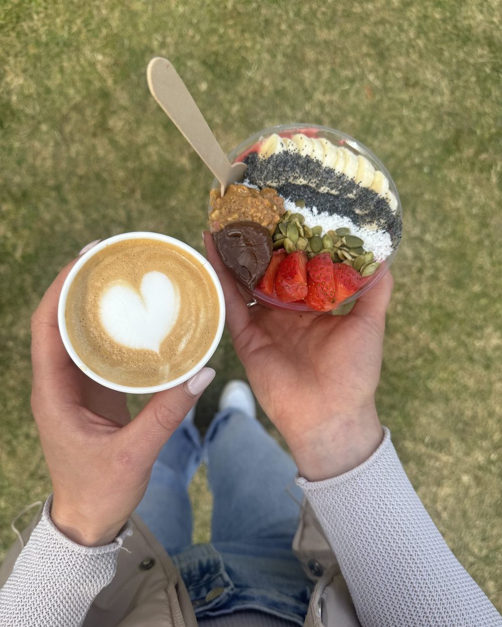 A heart latte held beside an açaí bowl